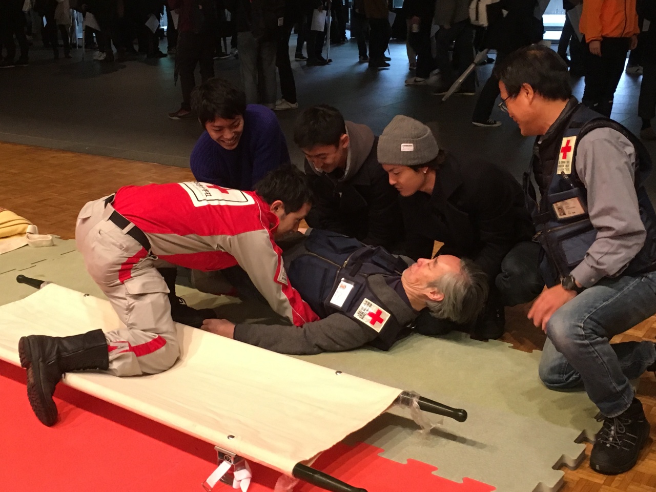 学園の防災訓練で日本赤十字社東京都支部指導員から担架搬送法を学ぶ学生達